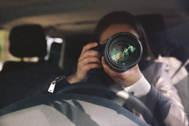 Private detective with camera spying from car